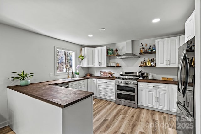 kitchen with white cabinetry, stainless steel appliances, sink, and wall chimney exhaust hood