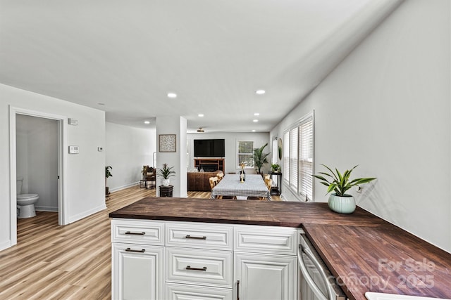 kitchen with dishwasher, white cabinetry, butcher block counters, and light hardwood / wood-style floors