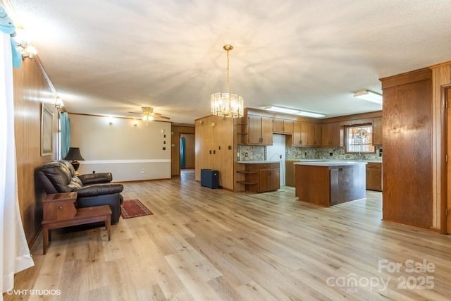 kitchen with pendant lighting, tasteful backsplash, a center island, and light wood-type flooring