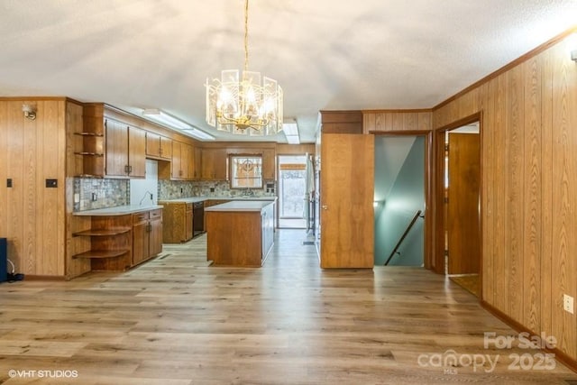 kitchen featuring wooden walls, decorative light fixtures, a center island, and light hardwood / wood-style flooring