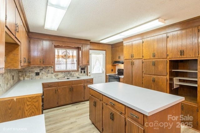 kitchen with sink, tasteful backsplash, light wood-type flooring, a kitchen island, and black range with electric stovetop