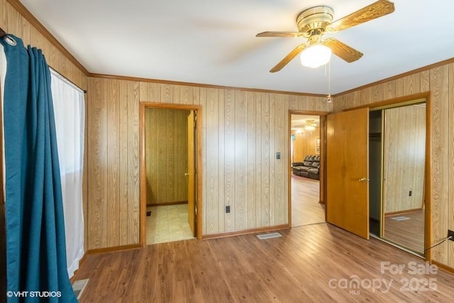 unfurnished bedroom with ceiling fan, a closet, ornamental molding, and light hardwood / wood-style flooring