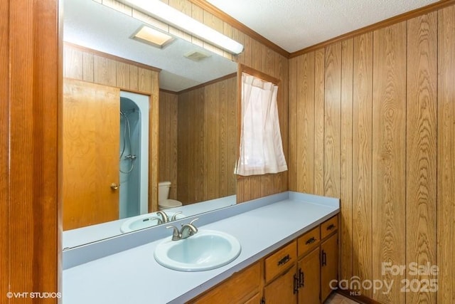 bathroom featuring crown molding, vanity, wooden walls, and toilet