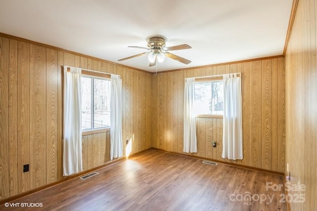 unfurnished room featuring crown molding, ceiling fan, hardwood / wood-style flooring, and a healthy amount of sunlight