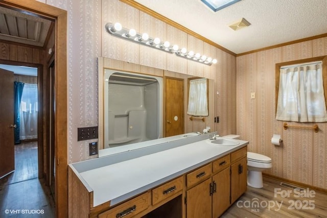 bathroom with vanity, wood-type flooring, ornamental molding, a textured ceiling, and toilet