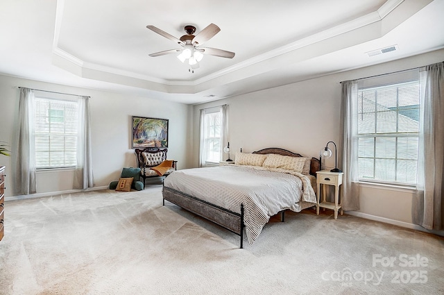 bedroom featuring light carpet, a tray ceiling, multiple windows, and visible vents