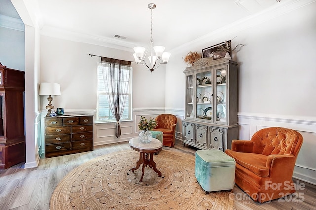 sitting room with ornamental molding, wainscoting, wood finished floors, and visible vents