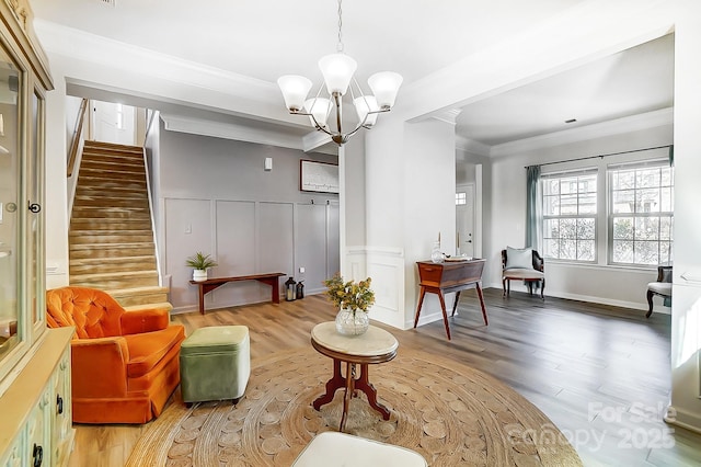 sitting room with crown molding, decorative columns, a decorative wall, stairway, and wood finished floors