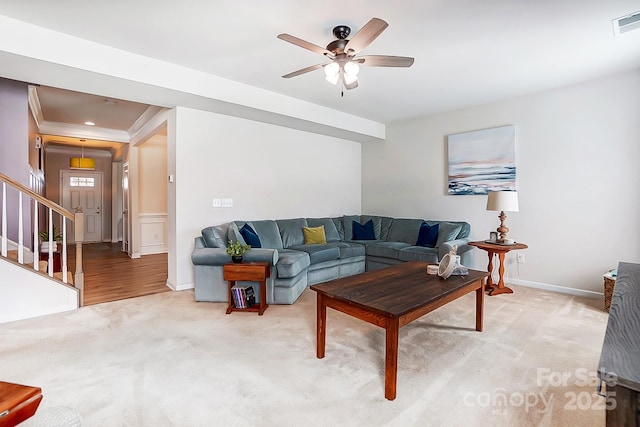 living room with light carpet, baseboards, a ceiling fan, stairway, and crown molding