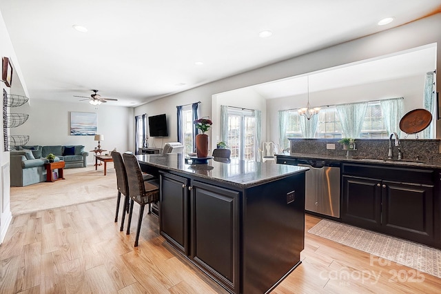 kitchen with dishwasher, dark cabinetry, light wood finished floors, and a sink