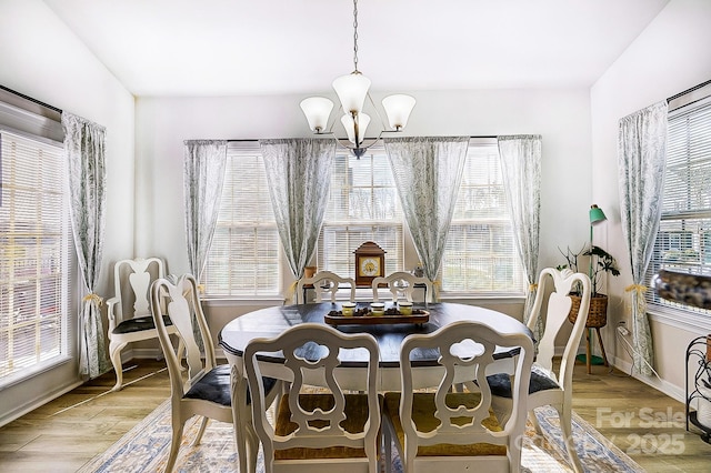 dining space with a chandelier, light wood-style floors, and baseboards