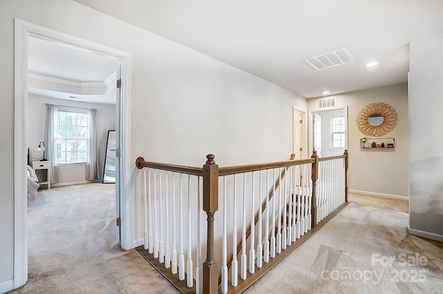 hallway featuring carpet floors, visible vents, an upstairs landing, and baseboards