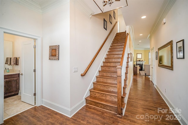 stairs with ornamental molding and hardwood / wood-style floors