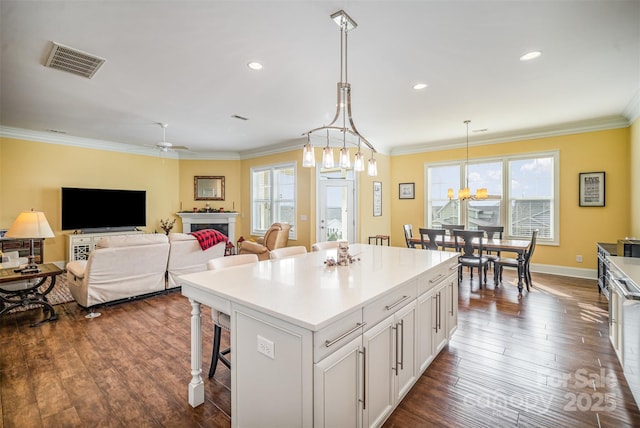 kitchen with a breakfast bar area, white cabinetry, ornamental molding, a kitchen island, and pendant lighting