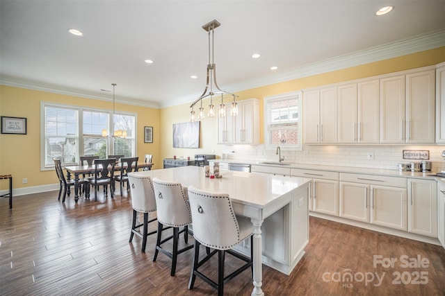 kitchen featuring white cabinetry, decorative light fixtures, sink, and a kitchen island