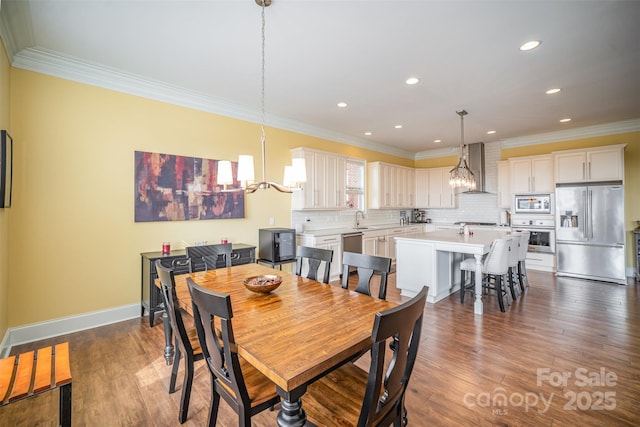 dining space with a notable chandelier, crown molding, dark wood-type flooring, and sink