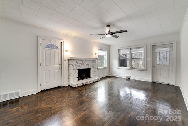 unfurnished living room featuring ceiling fan, dark hardwood / wood-style floors, and a stone fireplace