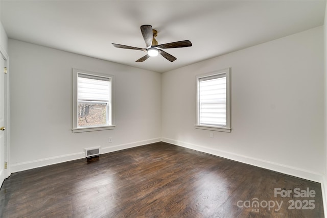 empty room featuring plenty of natural light, dark hardwood / wood-style floors, and ceiling fan