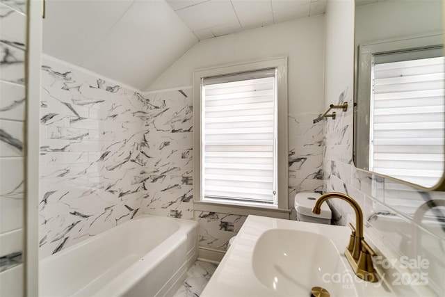 bathroom featuring lofted ceiling, tile walls, vanity, a tub, and toilet