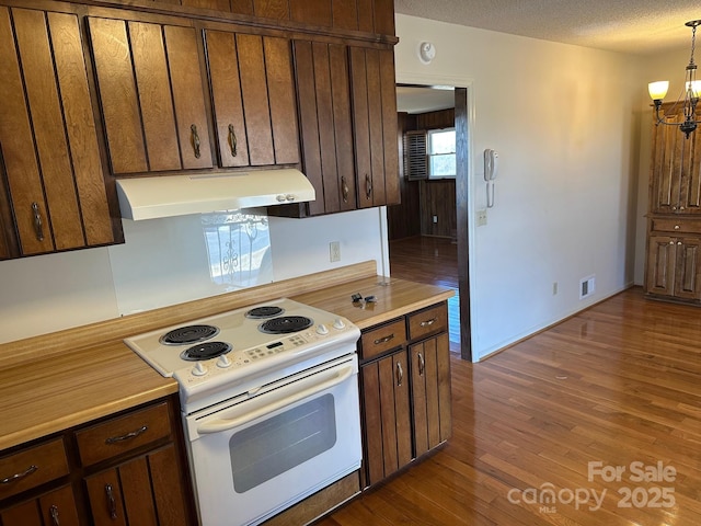 kitchen with dark wood-type flooring, an inviting chandelier, decorative light fixtures, a textured ceiling, and electric stove