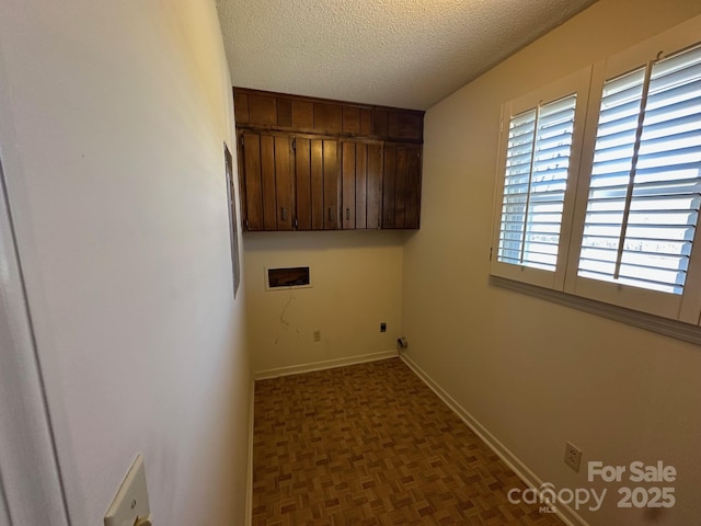 clothes washing area with electric dryer hookup, cabinets, washer hookup, dark parquet flooring, and a textured ceiling