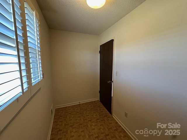 hall with dark parquet flooring and a textured ceiling