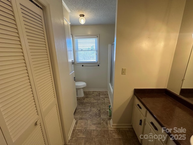 bathroom with vanity, toilet, and a textured ceiling