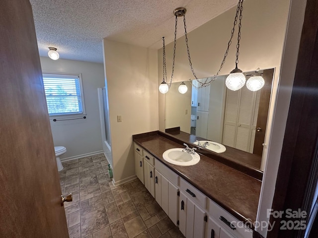 bathroom with walk in shower, vanity, toilet, and a textured ceiling