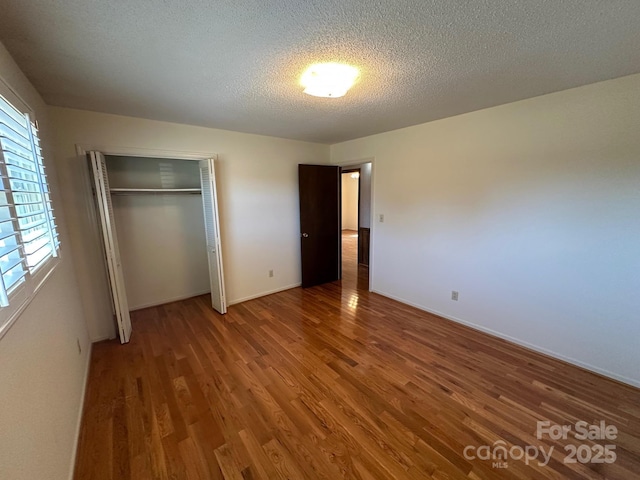 unfurnished bedroom featuring hardwood / wood-style floors, a closet, and a textured ceiling