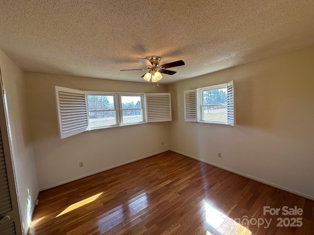 unfurnished room with a textured ceiling, dark wood-type flooring, and ceiling fan