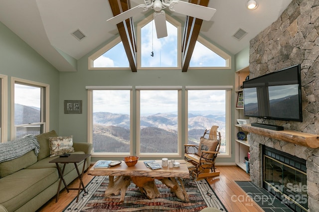 living room with ceiling fan, lofted ceiling, a fireplace, and light hardwood / wood-style flooring