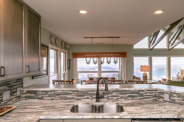 kitchen featuring sink, a chandelier, hanging light fixtures, a mountain view, and decorative backsplash