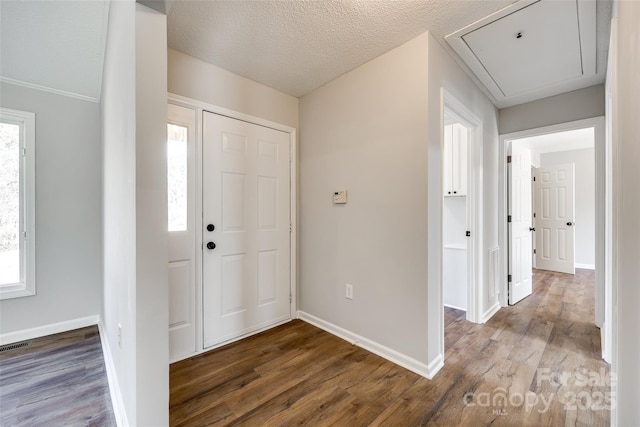 foyer with visible vents, a textured ceiling, baseboards, and wood finished floors