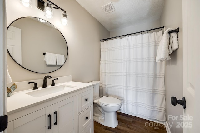 full bathroom with a textured ceiling, toilet, wood finished floors, vanity, and visible vents