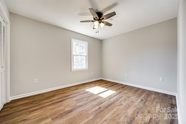 unfurnished bedroom with a ceiling fan, a closet, baseboards, and wood finished floors