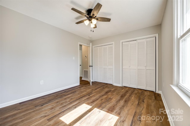 unfurnished bedroom featuring multiple closets, visible vents, baseboards, and multiple windows