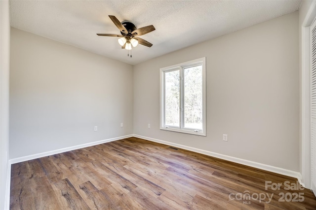 empty room with baseboards, visible vents, ceiling fan, and wood finished floors