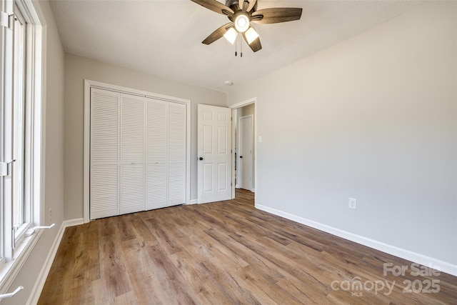 unfurnished bedroom with a closet, wood finished floors, a ceiling fan, and baseboards