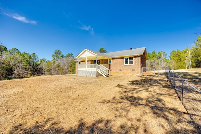 rear view of house with covered porch, brick siding, fence, stairs, and crawl space