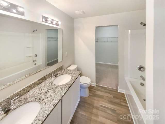 full bathroom with vanity, hardwood / wood-style floors, washtub / shower combination, and toilet