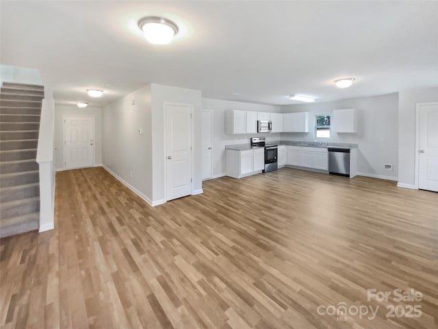 unfurnished living room featuring sink and light hardwood / wood-style floors