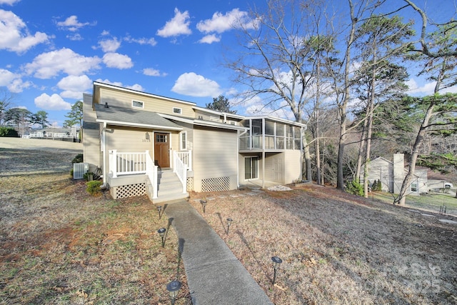 view of front of house with central AC and a sunroom