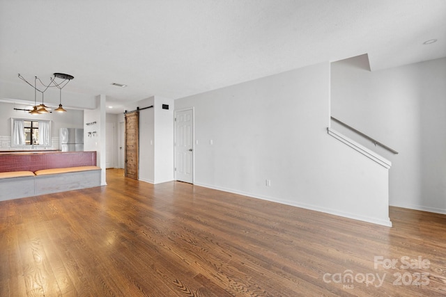 505 Victory Trl, Morganton, NC 28655 - unfurnished living room with visible vents, baseboards, a barn door, and wood finished floors