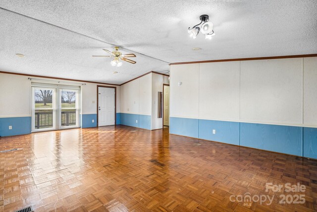 spare room featuring a textured ceiling, crown molding, wainscoting, and ceiling fan