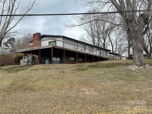 back of property featuring a wooden deck and a lawn