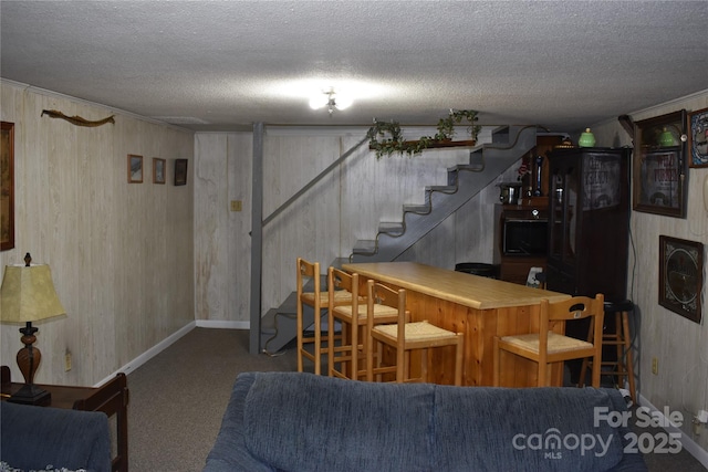 bar featuring carpet flooring, a textured ceiling, and wood walls