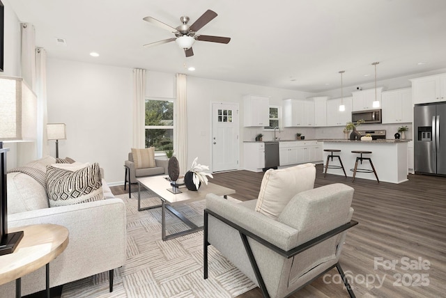 living room with ceiling fan, sink, and light wood-type flooring