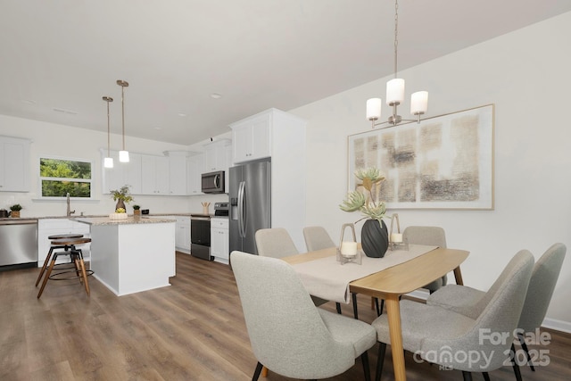 dining area with hardwood / wood-style flooring, an inviting chandelier, and sink