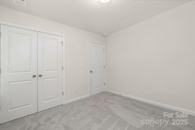 unfurnished bedroom with light colored carpet and a closet