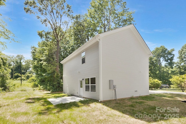 view of side of home with a yard and a patio area